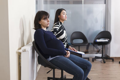 Side view of pregnant woman sitting on chair