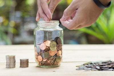 Cropped hands putting coins in jar