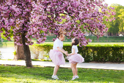 Full length of girls playing by flowering tree