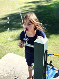 High angle view of girl standing by drinking fountain