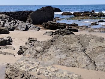 Rocks on shore by sea against sky