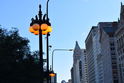 Low angle view of illuminated street light and buildings against sky