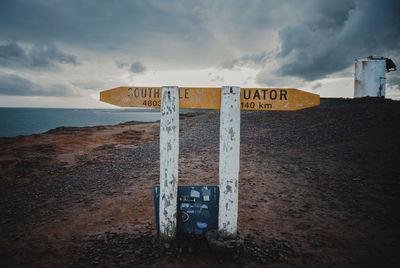 Information sign on beach against sky