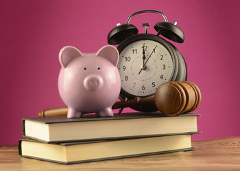 Stack of books on table against pink background