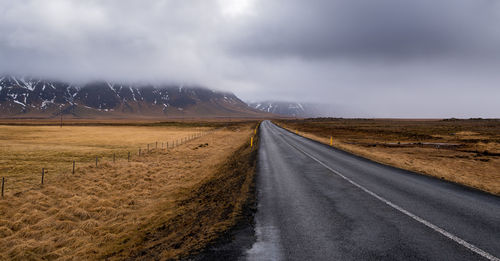 Empty road amidst land against sky