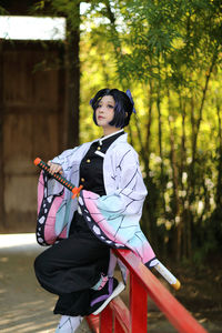 Young woman standing against trees