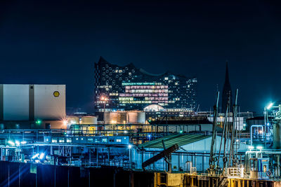 Illuminated factory against sky at night