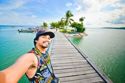 Portrait of man standing on pier over sea against sky