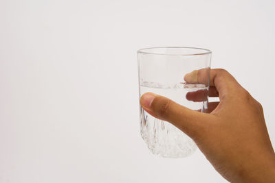 Close-up of hand holding drink against white background