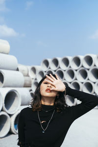 Portrait of young woman standing against sky