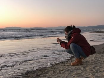 Woman on beach against sky during sunset