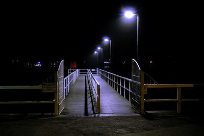 Empty footpath in illuminated city at night
