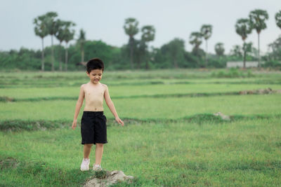 Full length of shirtless boy standing on field