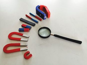 High angle view of magnets by magnifying glass on table