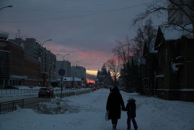 People walking on snow covered city during winter