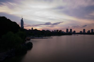 River amidst buildings against sky during sunset