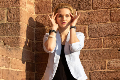 Portrait of young woman standing against wall