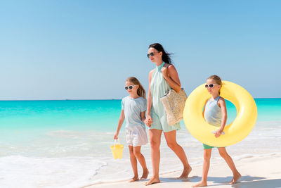 Mother and daughters walking on beach