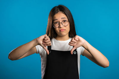 Portrait of teenage girl standing against blue background