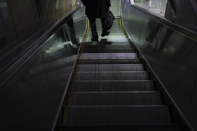 Low section of man walking on escalator