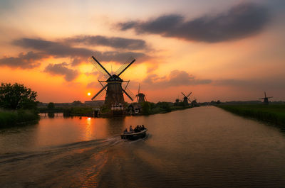 Motorboat sailing on river by traditional windmill