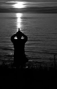 Silhouette man on lake against sky during sunset