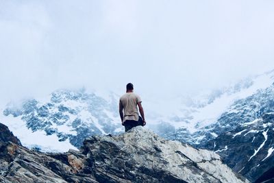 Rear view of man on snowcapped mountain against sky