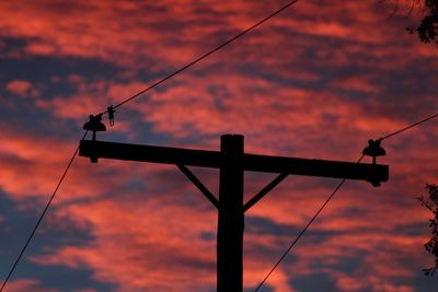 Low angle view of silhouette crane against cloudy sky during sunset