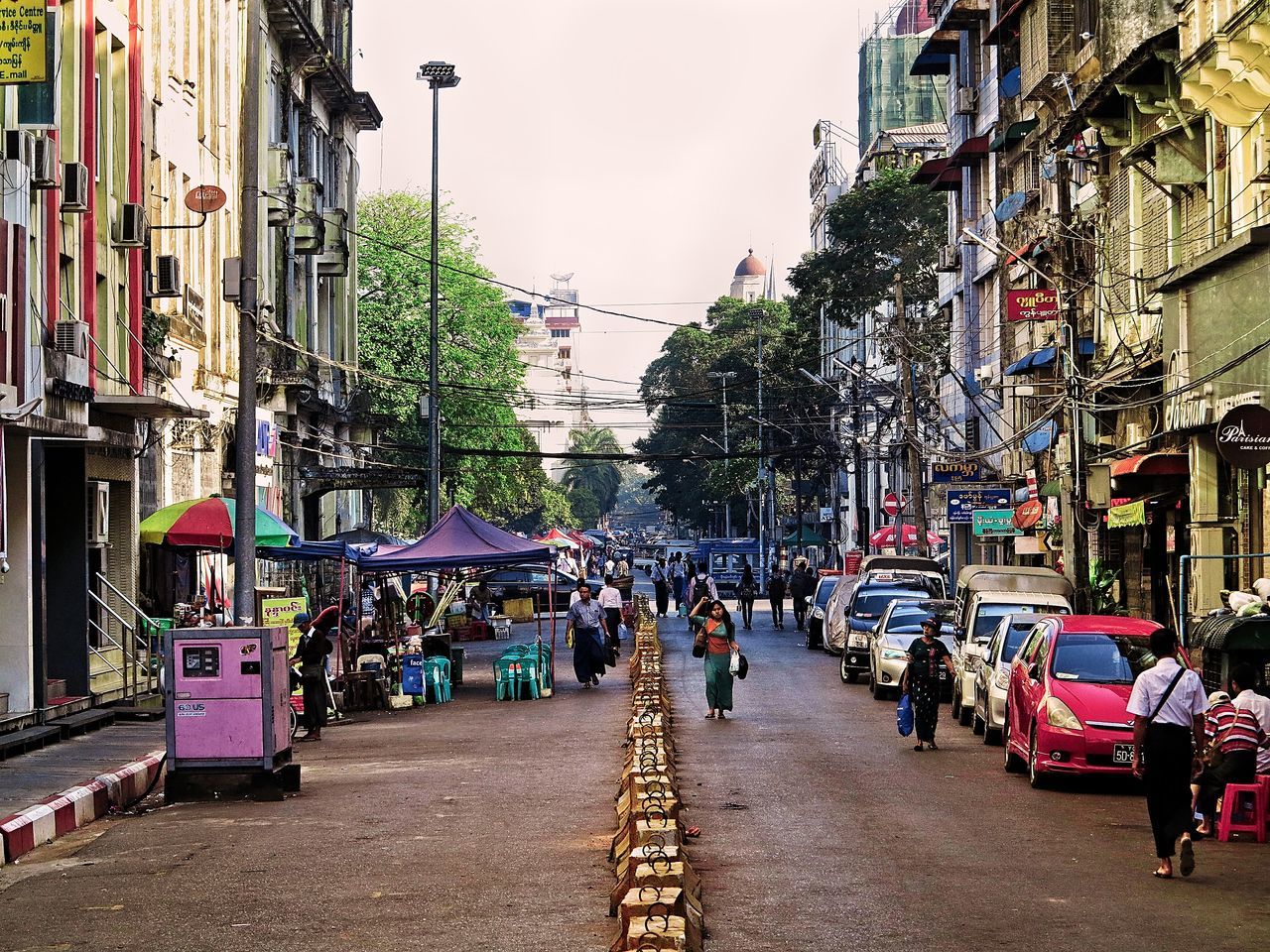 PEOPLE ON CITY STREET BY BUILDINGS AGAINST SKY IN BACKGROUND