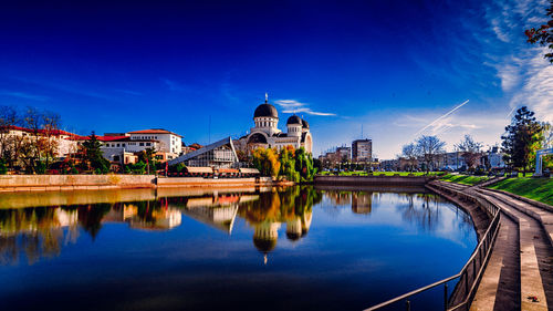 Arch bridge over river against blue sky in city