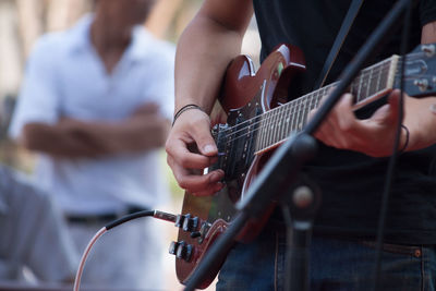 Midsection of man playing electric guitar