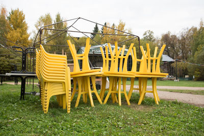 Empty chairs in park against sky