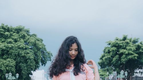 Portrait of young woman standing against sky