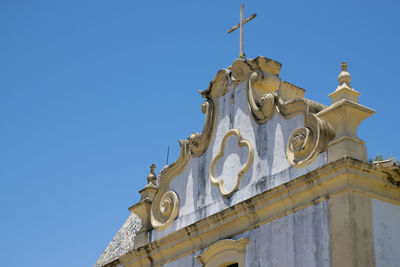 Low angle view of religious cross on building against clear blue sky