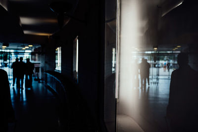 Rear view of silhouette people walking in illuminated corridor