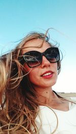Portrait of young woman wearing sunglasses against sky