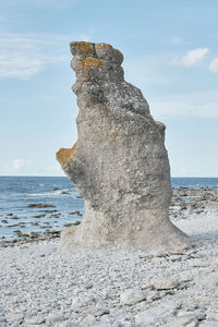 Rock formation on beach against sky