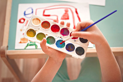 Midsection of person holding painting on table