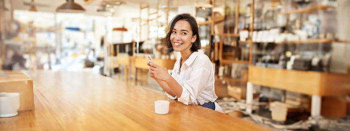 Portrait of young woman standing in cafe