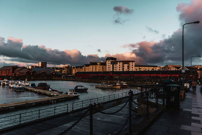 Bridge over river in city against sky during sunset