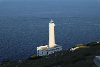 High angle view of lighthouse by sea against buildings