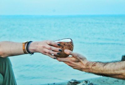 Man holding hands against sea against sky