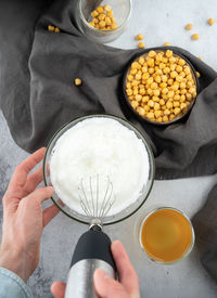 Chickpea aquafaba. egg replacement. vegan. men hands whippe whisk chickpeas liquid in glass bowl