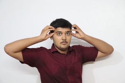 Portrait of young man standing against white background