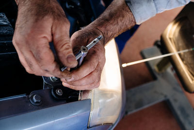 Cropped image of hands repairing car at garage