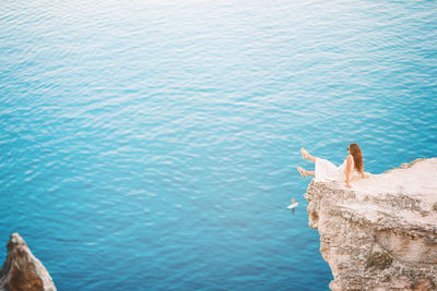 High angle view of woman on rock by sea