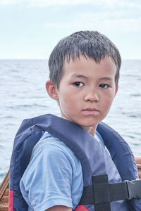 Portrait of boy looking away by sea