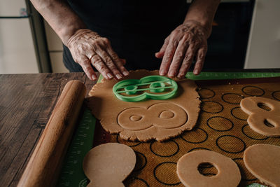 Grandmother makes gingerbread cookies with hands and cuts out figure eights for march 8
