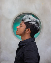 Side view of young man against wall