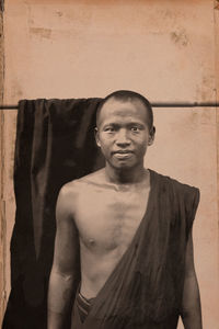 Portrait of shirtless man standing against wall